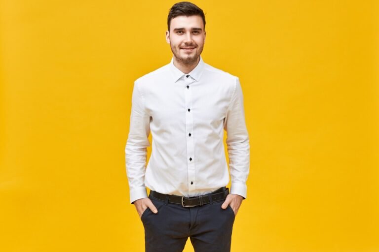 positive-confident-young-caucasian-male-office-worker-wearing-white-formal-shirt-classic-trousers-with-belt-having-happy-facial-expression-keeping-hands-pockets-smiling-joyfully_343059-4600